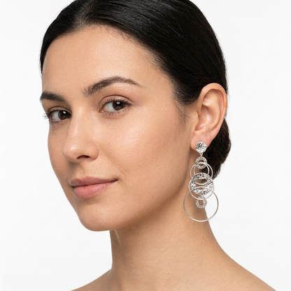 Modelka z wiszącym kolczykiem z połączonych kółek w srebrnym kolorze na białym tle